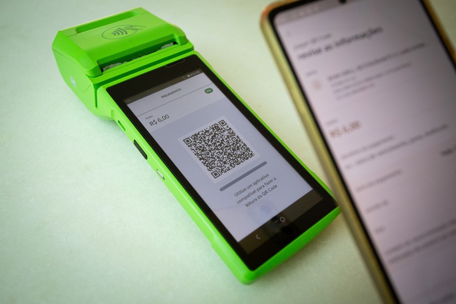 Celular e terminal de pagamento em operação relacionada ao novo limite do Pix por aproximação